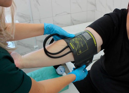 Предварительный осмотр пациента Врач измеряет давление пациенту